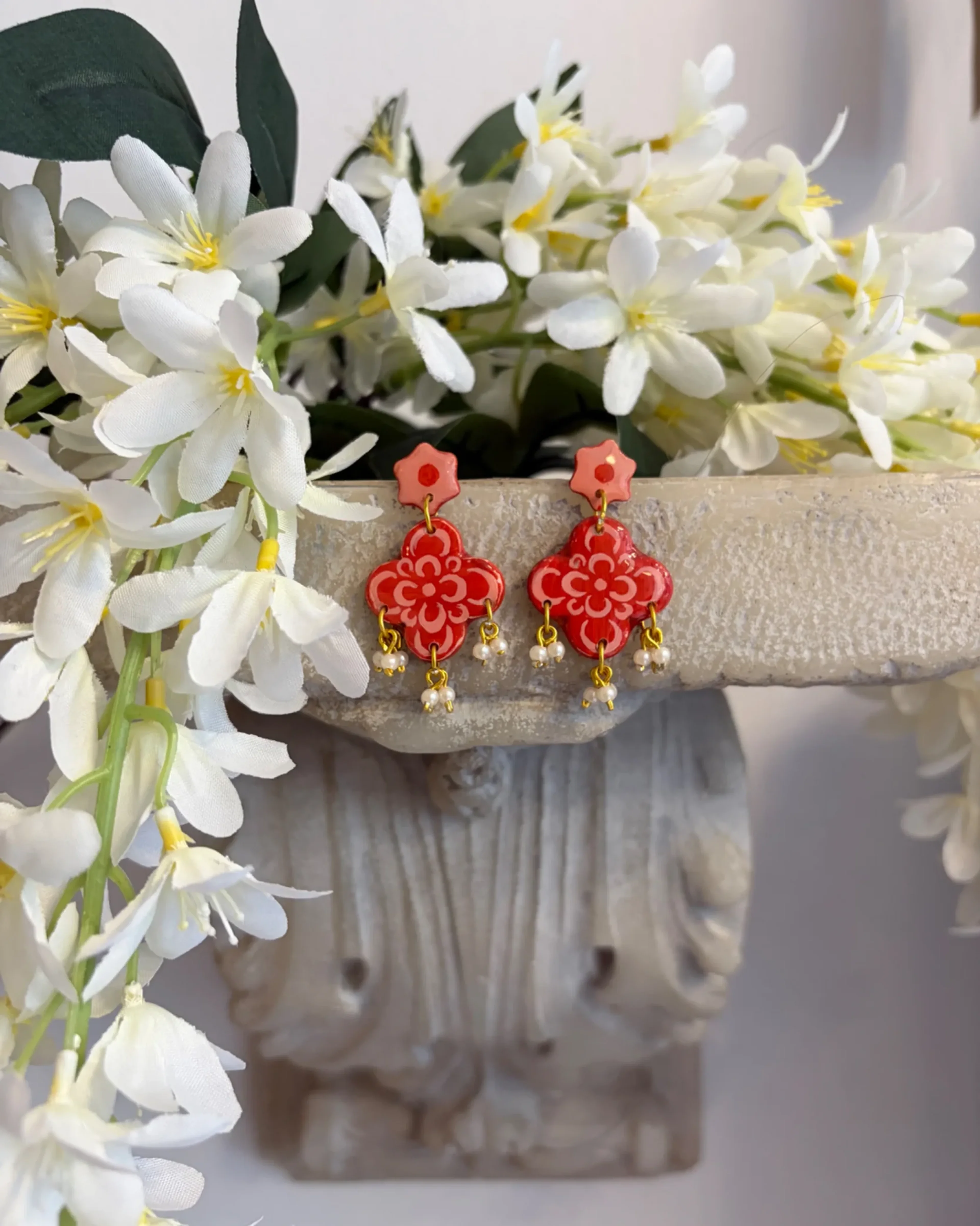 The Jaipur Pink earrings hung beside a stone urn and white flowers
