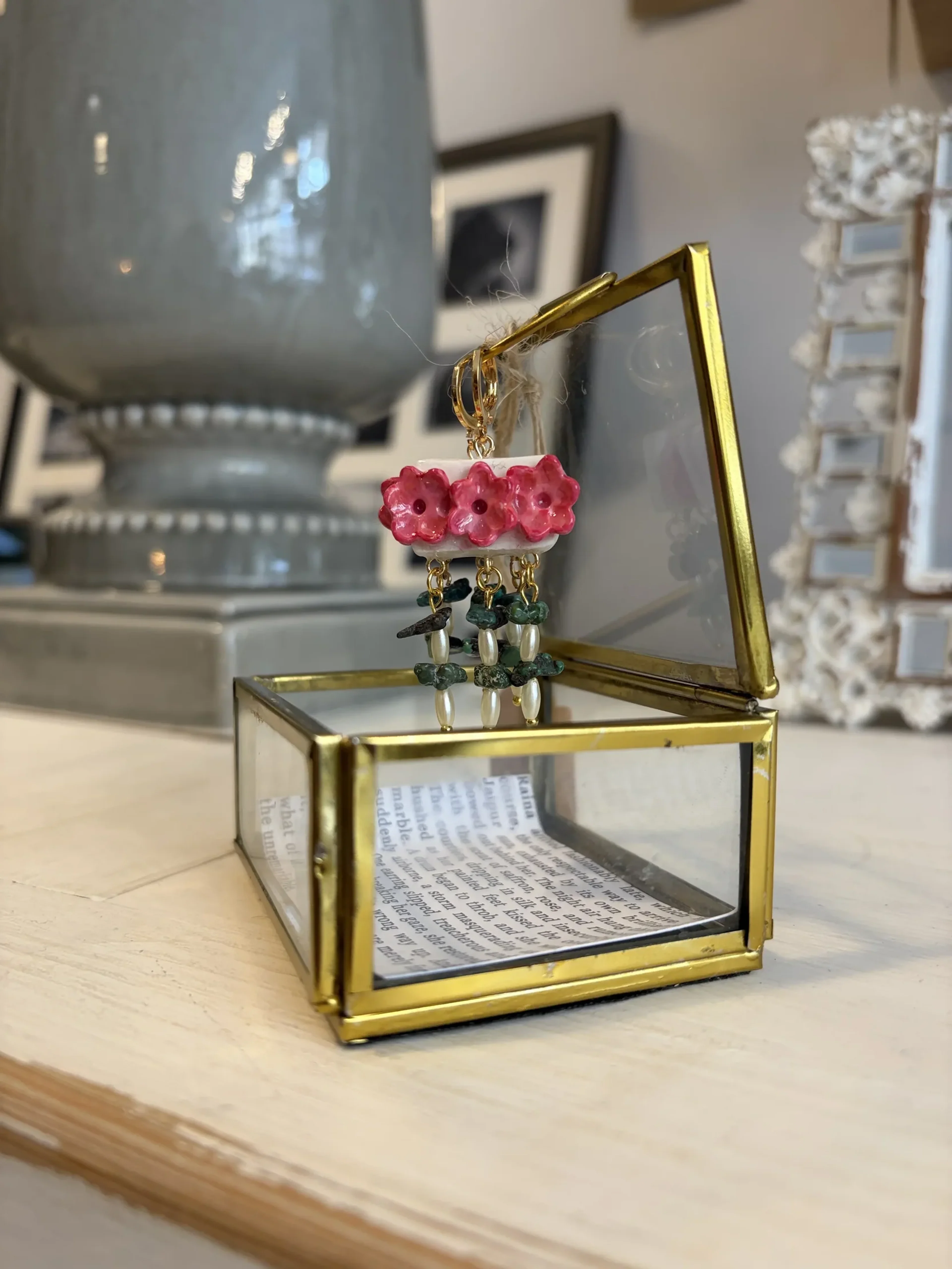 The same earrings displayed in their hinged brass-and-glass box